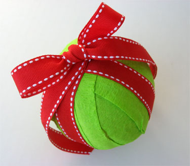 green ornament wrapped with red ribbon