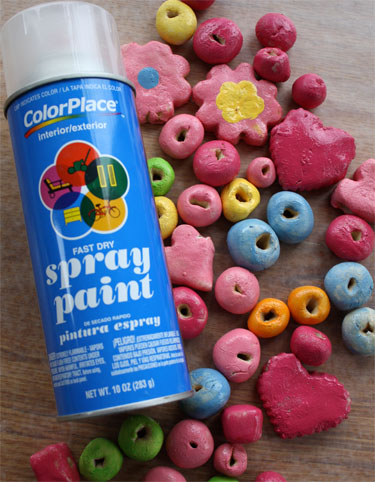 spray paint in foreground and colorfully baked salt dough beads in background 