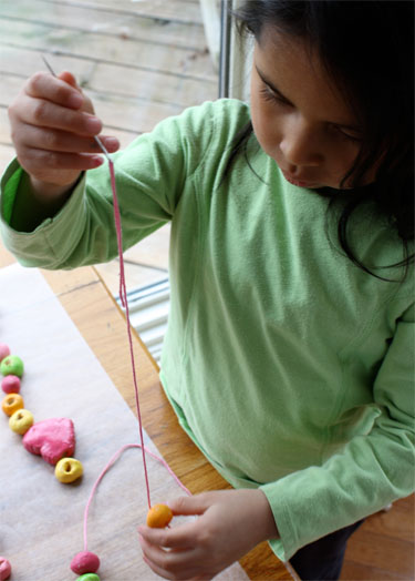 overhead photo of child threading salt dough beads 