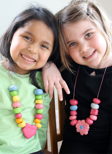 two young girls smiling and wearing their colorfully painted salt bead necklaces 