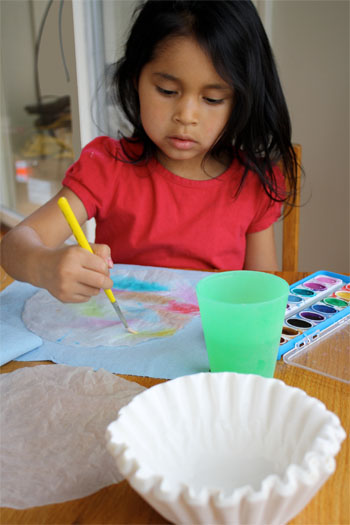 a child painting coffee filter for butterfly craft 