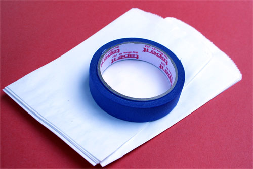 a roll of blue tape laying on top of a stack of white sandwich bags