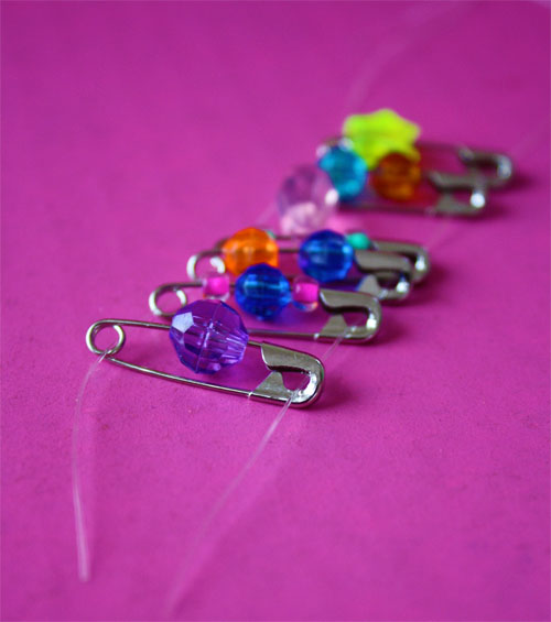 safety pins with beads laying on a table 