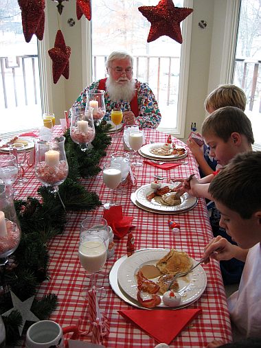 Breakfast with Santa- Santa at table with boys. Red stars hanging from the ceiling. -Skip To My Lou