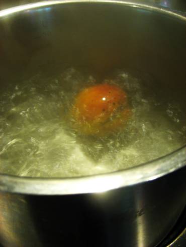 Peach dipped in boiling water in a large pot to make peeling easier.