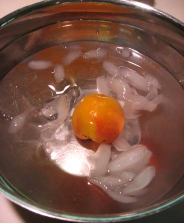 Peach in ice bath in a large bowl.