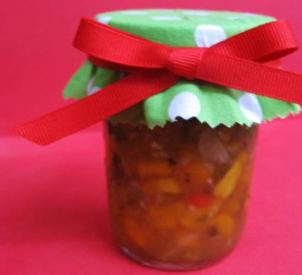 Peach Salsa in canning jar with top covered with green with white polka dot fabric and tied with a red ribbon.