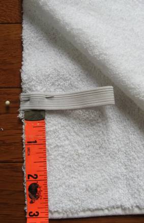 6-inch piece of elastic folded in half and pinned to the long end of the towel where the back of the head goes 3 inches in from the edge of the fabric with a seam