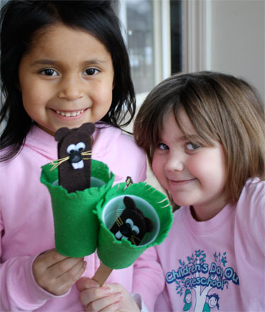 two kids holding groundhog puppets for groundhog day