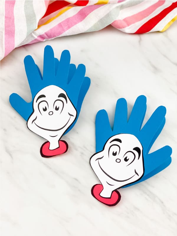 celecbrate dr seuss with these handprint "Thing 1 and Thing 2" cards; the card is made of hand cut out of blue construction paper with printable faces glued to the palm region of the hand