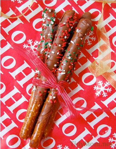 chocolate dipped pretzel rods tied with bow on ho ho ho wrapping paper