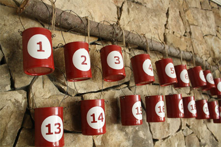 Recycled tin can advent calendar hanging from a wall