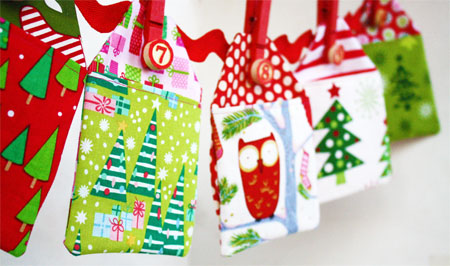 Fabric advent calendars with festive decoration hanging from a wall