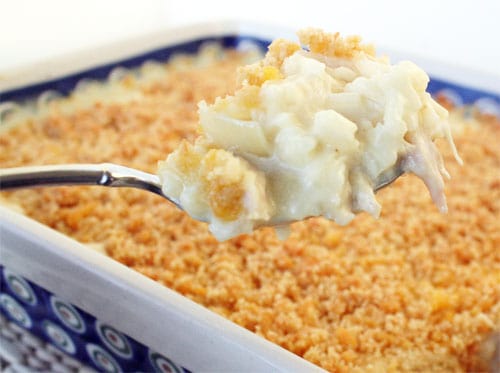 Chicken and rice casserole recipe prepared in a 9 by 13 glass pan with a spoonful lifted out. -Skip To My Lou