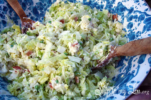 Tossed cauliflower salad with wooden salad forks in a blue and white bowl.