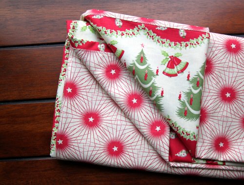 Folded Holiday Table Cloth showing details of vintage fabric with bursts of stars, Christmas trees, and bells. -Skip To my Lou