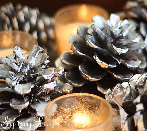 Image shows a pinecone decoration next to some candles. Skip to my lou.