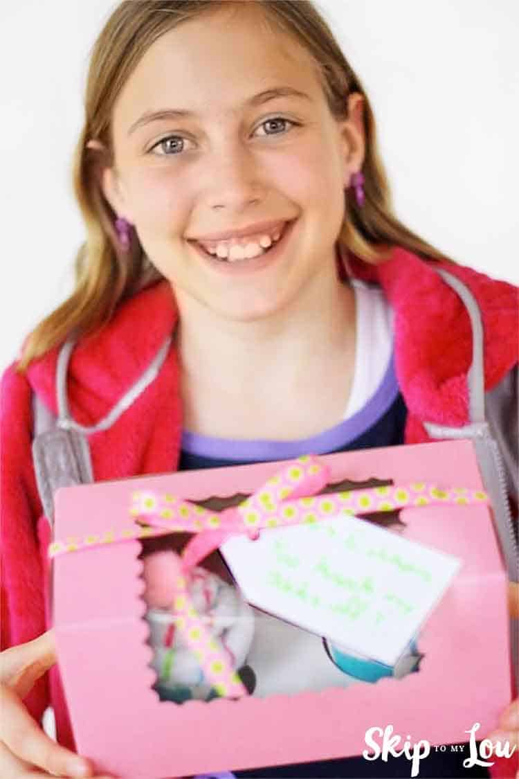 child holding sock cupcakes in bakery box