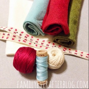 Supplies for the ornament gathered together. Light blue felt, red felt, green felt, Santa ribbon, red thread, white thread, and light bule thread.  