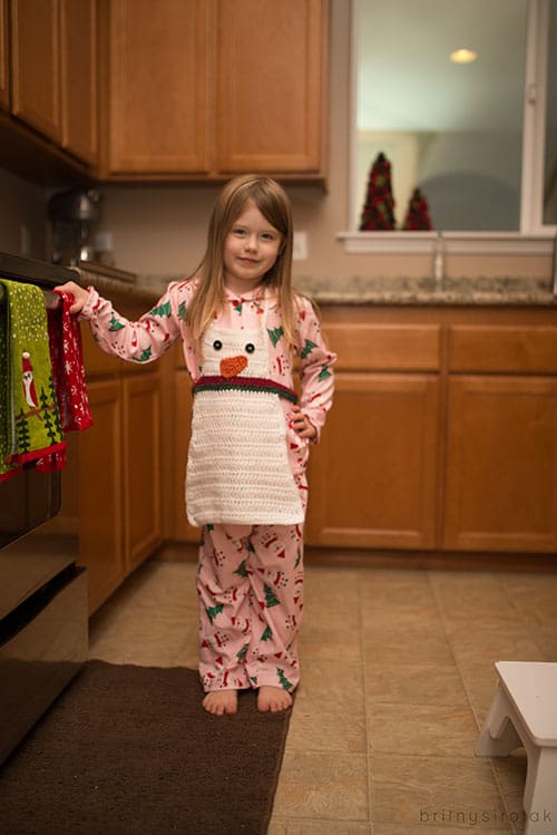 crochet-snowman-apron on a little girl in the kitchen skip to my lou
