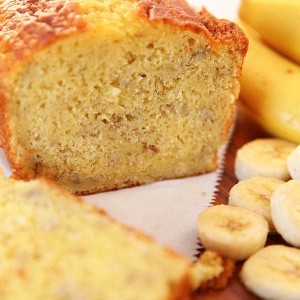 Banana Bread made with a cake mix with bananas in the background. -Skip To My Lou
