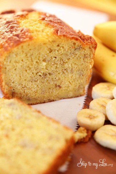 Banana Bread made with a cake mix with bananas in the background. -Skip To My Lou