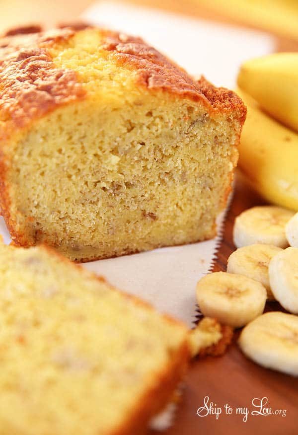 Banana Bread made with a cake mix with bananas in the background. -Skip To My Lou