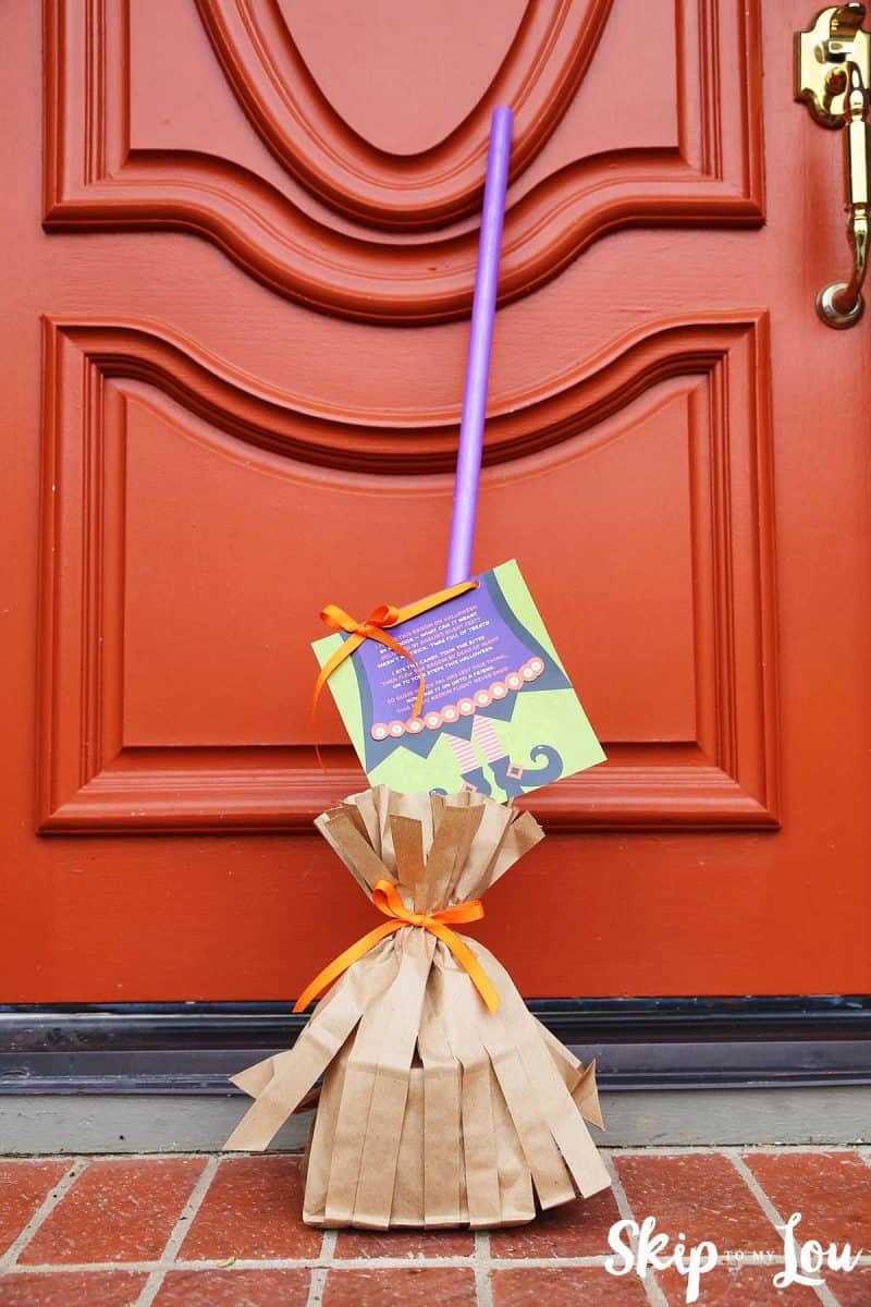 magic broom treat with poem attached position on the a front stoop with at red door behind it