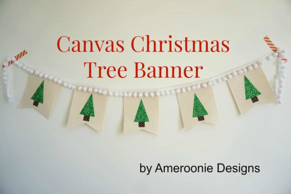 A Christmas Tree Banner made from canvas taped to the wall with striped tape. The banner has white pom poms on top.