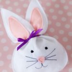 white felt bunny treat bag laying on a pink polka dot table covering