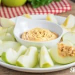 apple dip in white bold with granny smith apples on a plate around the dip