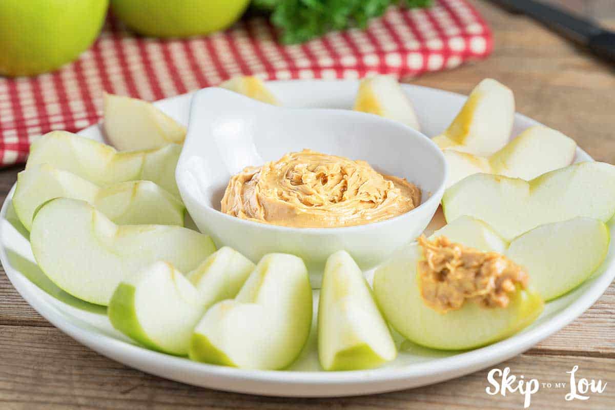 apple dip in white bold with granny smith apples on a plate around the dip