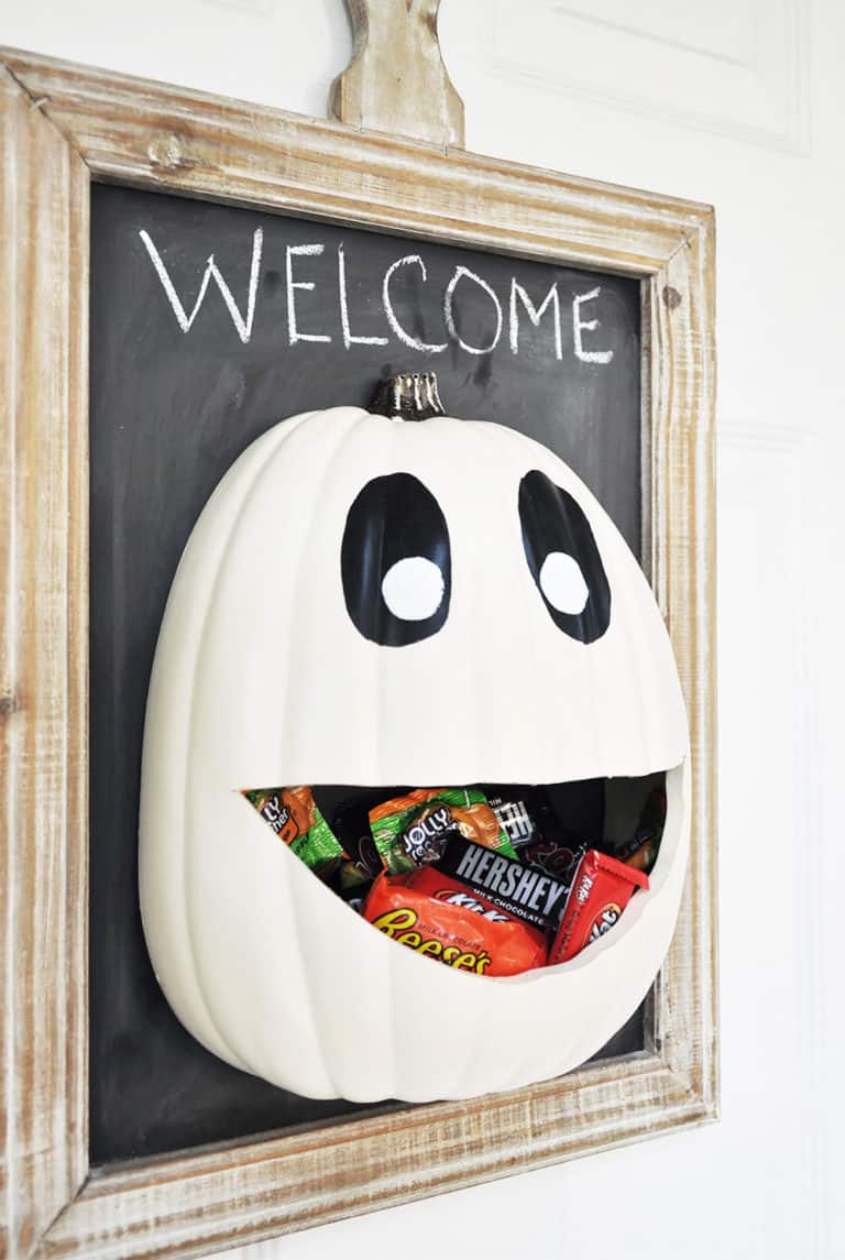 Candy door hanger - white pumpkin face basket filled with candy attached to a chalk board with a welcome writer in chalk