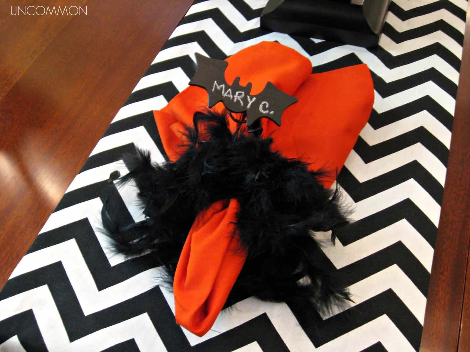 Flying bat napkin ring wrapped around orange napkin on a black and white chevron table cloth