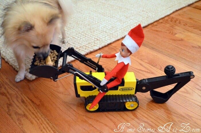 elf riding on tractor with a load full of dog food - a dog is eating out of the scoop
