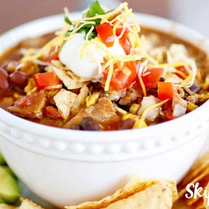 slow cooker chicken taco soup with avacado and tortilla chips on the side