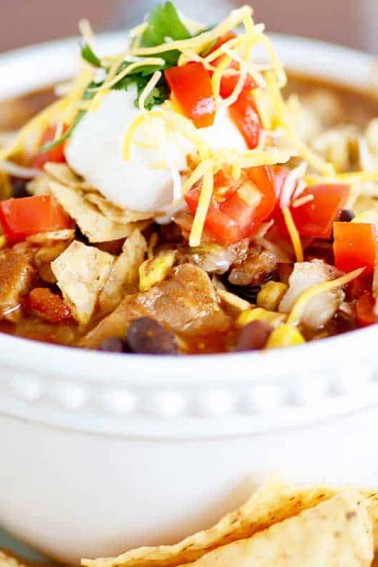 slow cooker chicken taco soup with avacado and tortilla chips on the side