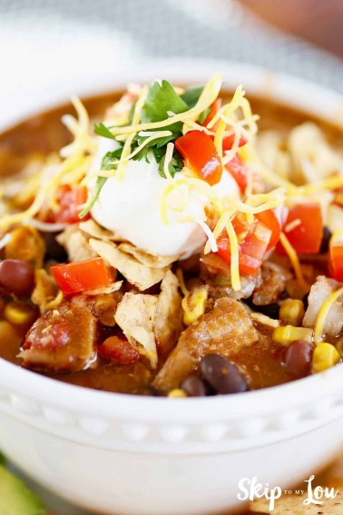 chicken taco soup topped with sour cream and tortilla chips
