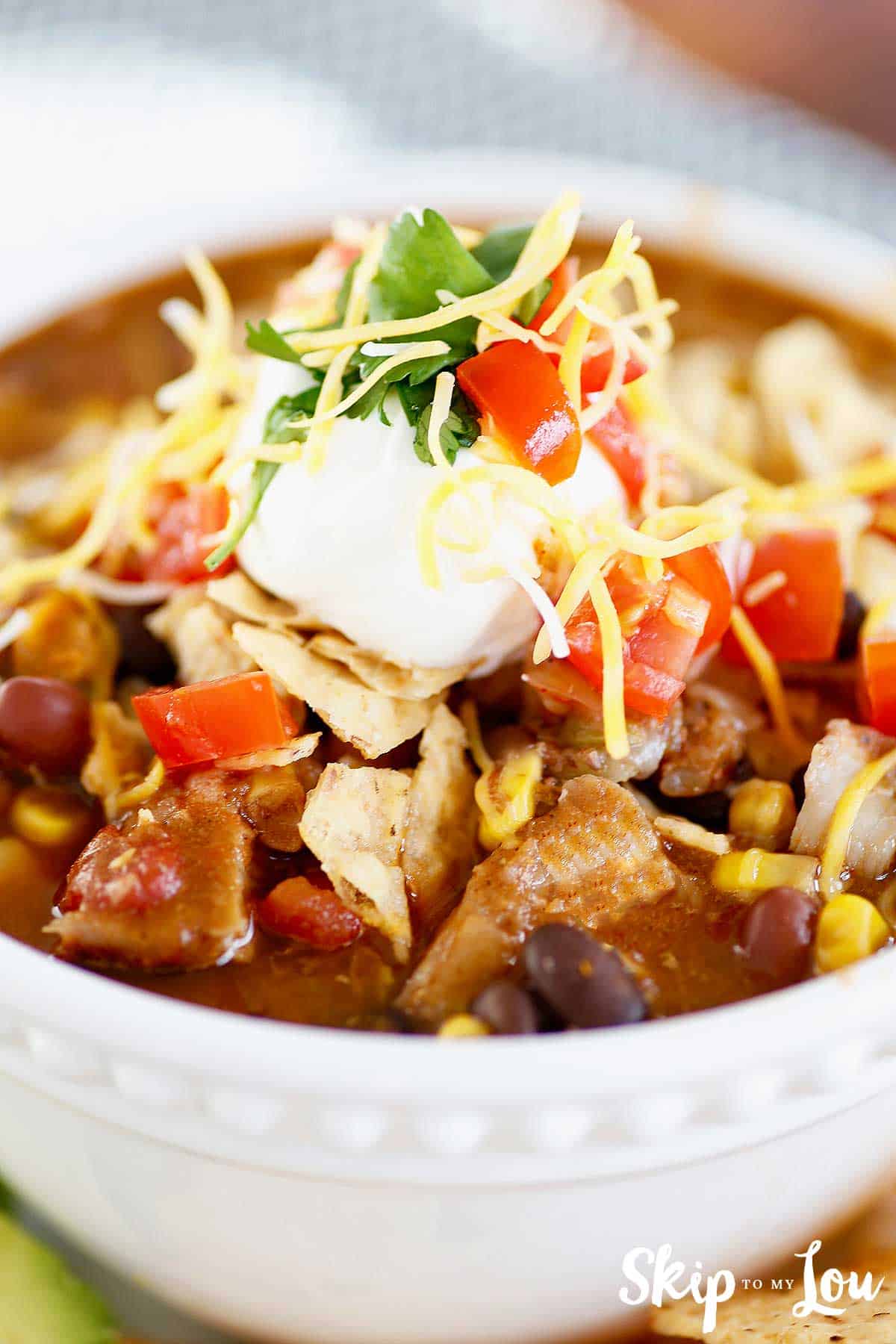 chicken taco soup topped with sour cream and tortilla chips