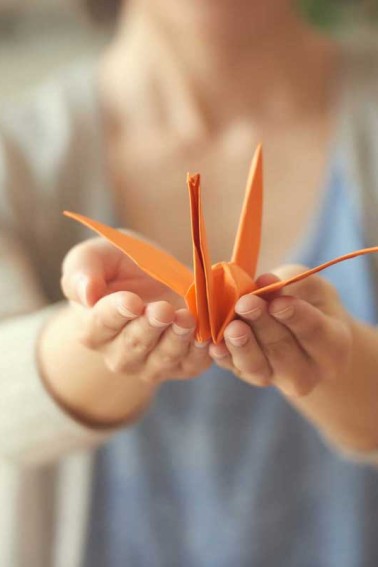 hands holding folded paper origami crane