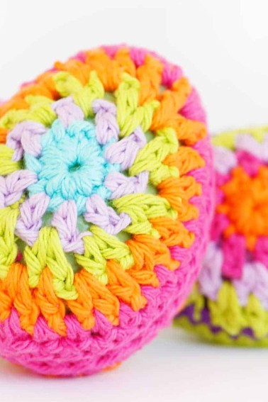 crochet egg with bright pink, orange, yellow, light pink, and light blue rings yarn