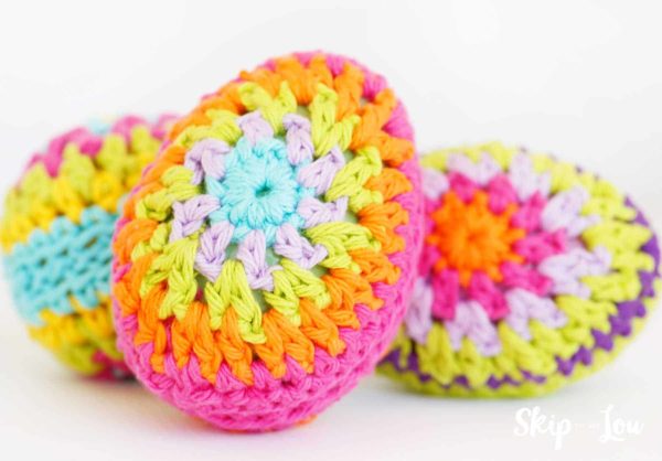 crochet egg with bright pink, orange, yellow, light pink, and light blue rings yarn