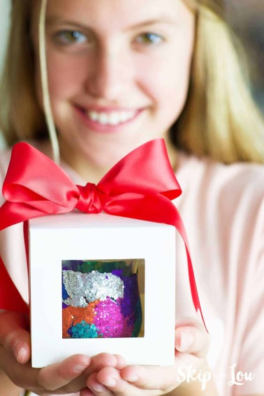 girl holding box with bow holding glitter votive