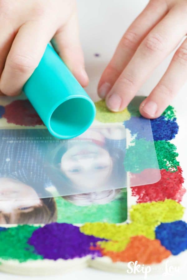rolling out glitter dots on wooden frame