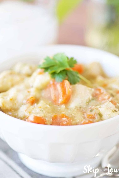 chicken and dumplings in white bowl with parsley on top