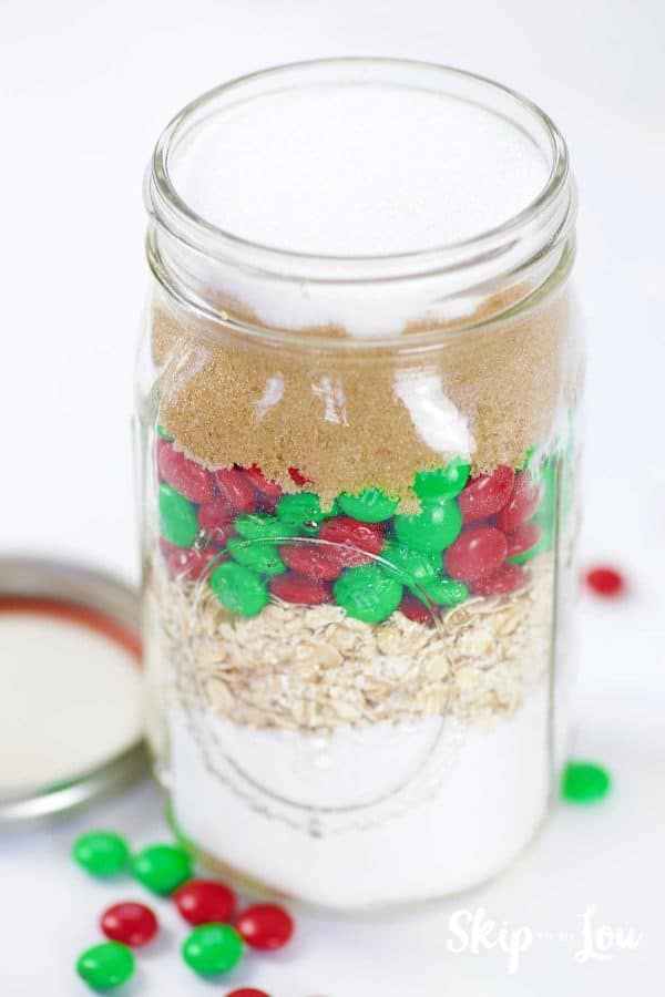 layered ingredients brown sugar, M&Ms , oats, flour and sugar mix in wide mouth mason jar