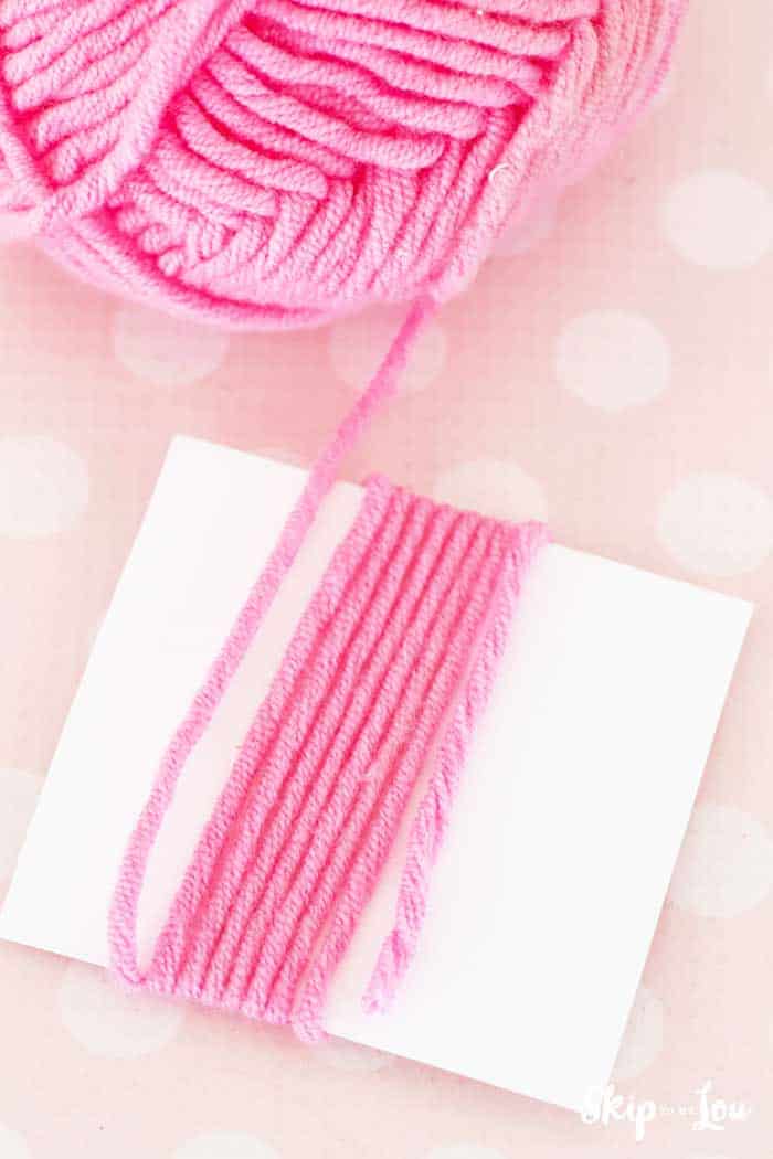 yarn ball yarn wrapped around white card to make DIY tassel