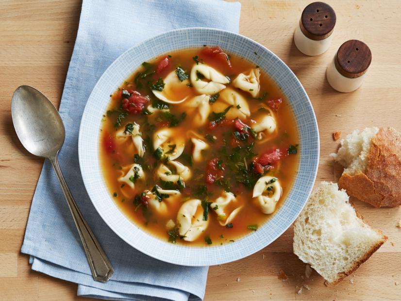 spinach tortellini soup in bowl with bread to the side