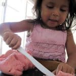 child cutting playdough
