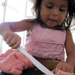 child cutting playdough